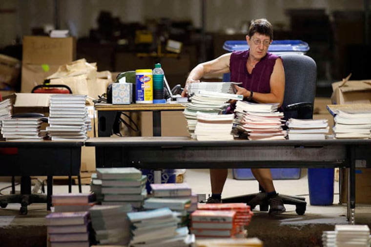 Connie Hoelscher moves books at School District headquarters. She is a volunteer and a librarian. (YONG KIM / Staff Photographer)