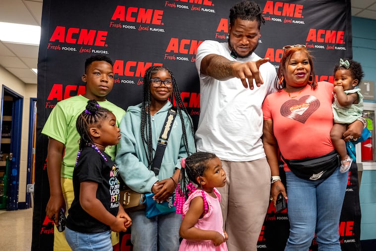 Shakila Moten (right) holds her 8-month-old granddaughter Ahimya, as she poses with Eagles defensive tackle Jalen Carter and the rest of her charges at a kick-off event Thursday.