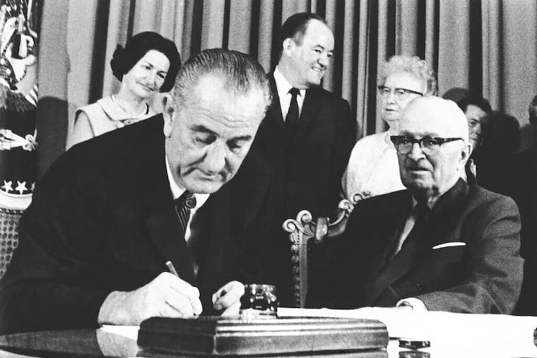 President Lyndon B. Johnson signs the Medicare bill in Independence, Mo., July 30, 1965. At right is former President Harry Truman.