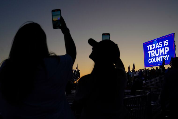 People hold their cellphones as they wait for the plane carrying former President Donald Trump to take off after a campaign rally at Waco Regional Airport on Saturday, March 25, 2023, in Waco, Texas.