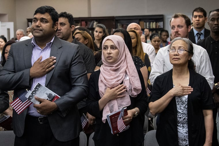 U.S. citizenship candidates take the oath of allegiance during a 2019 naturalization ceremony at the Historical Society in Philadelphia.