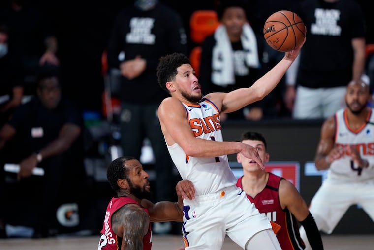 Devin Booker of the Suns goes to the basket over Miami's Andre Iguodala, left, and Tyler Herro during Phoenix's win on Saturday.
