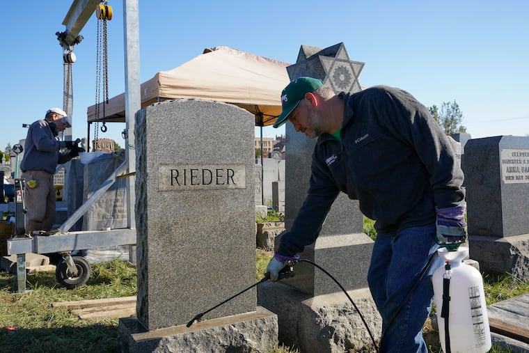 Joe Ferrannini (left) smooths the base of a gravestone, while Adam Denish cleans another at the Har Nebo Cemetery in Northeast Philadelphia. Ferrannini is a professional gravestone conservator and Denish is a volunteer; they are part of a pilot project coordinated by the Jewish Federation of Greater Philadelphia.