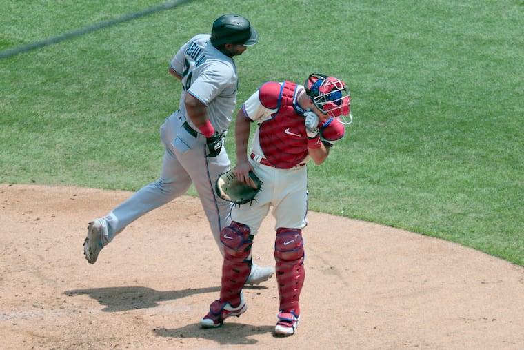 Phils catcher J.T. Realmuto spits as Marlins Jesus Aguilar crosses the plate after hitting a home run against the Phillies on Sunday.