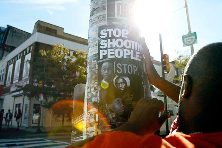 Terry Starks of Philadelphia Ceasefire tapes a poster to a pole near the scene of the subway shooting Wednesday, September 19, 2012. At least one teen was arrested. (Tom Gralish / Staff Photographer)