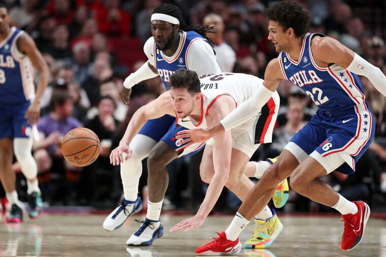 Philadelphia 76ers center Montrezl Harrell, left, and guard Matisse Thybulle, right, scramble for the ball alongside Portland Trail Blazers forward Drew Eubanks (24) during the first half of an NBA basketball game in Portland, Ore., Thursday.