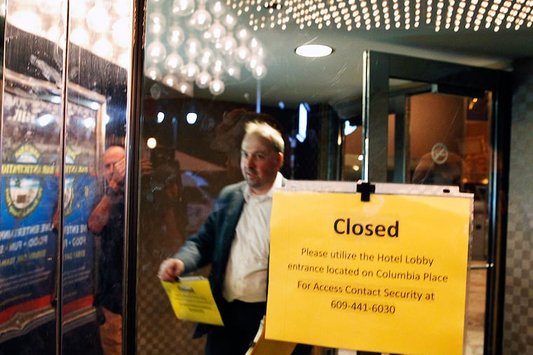 At 6 a.m. Tuesday, Trump Plaza employee Bill Norwood places closed signs on the Boardwalk of the Trump Plaza casino.