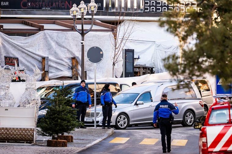 A hearse car drives as police officers inspect the area where a fire broke out at the Le Constellation bar and lounge during New Year's celebration, in Crans-Montana, Switzerland.
