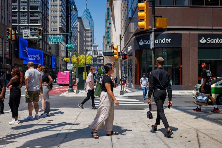 Women and men walk through Center City on a July weekday in this 2024 file photo. While the city's gender pay gap has narrowed, women still earn less than their male colleagues on average, according to a new report.