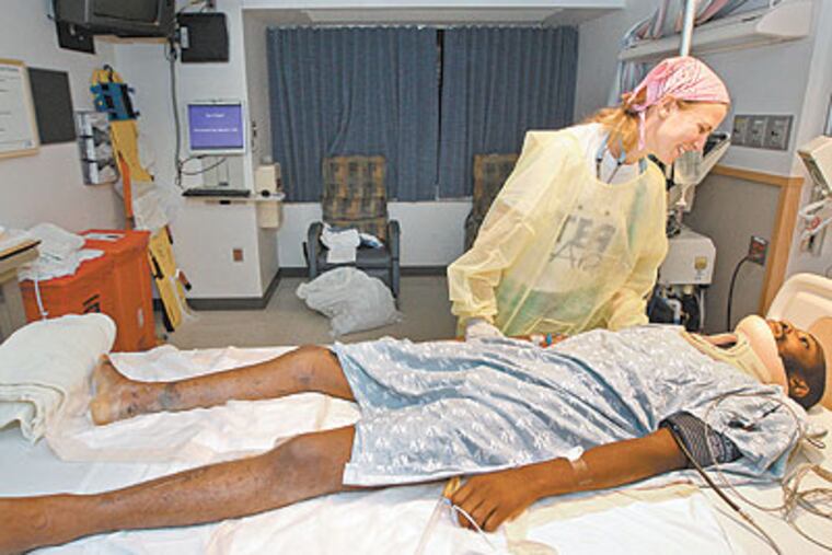 Dr. Katie Gollotto, who brought Wilner Pierre from Haiti to Jefferson Hospital, stands over him while he is being assessed in the Surgical Intensive Care Unit. (Michael Bryant / Staff Photographer)