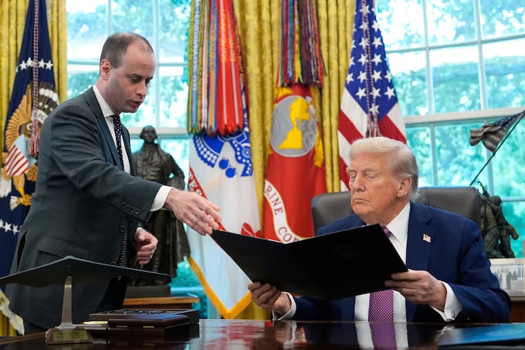White House staff secretary Will Scharf, left, hands President Donald Trump an executive order to sign in the Oval Office of the White House, Sept. 5, 2025, in Washington. On Sunday Trump named Scharf the new White House counsel.