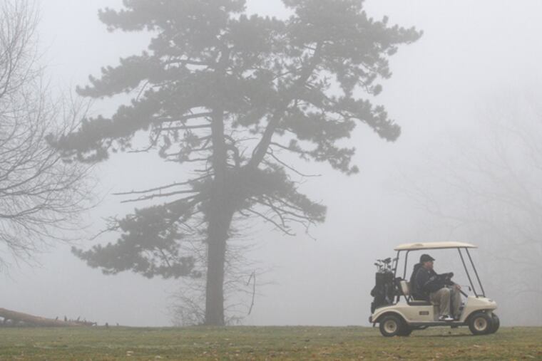 A golf cart makes its way through unexpected heavy fog at Cobbs Creek Golf Club in Fairmount Park. (Charles Fox / Staff Photographer)