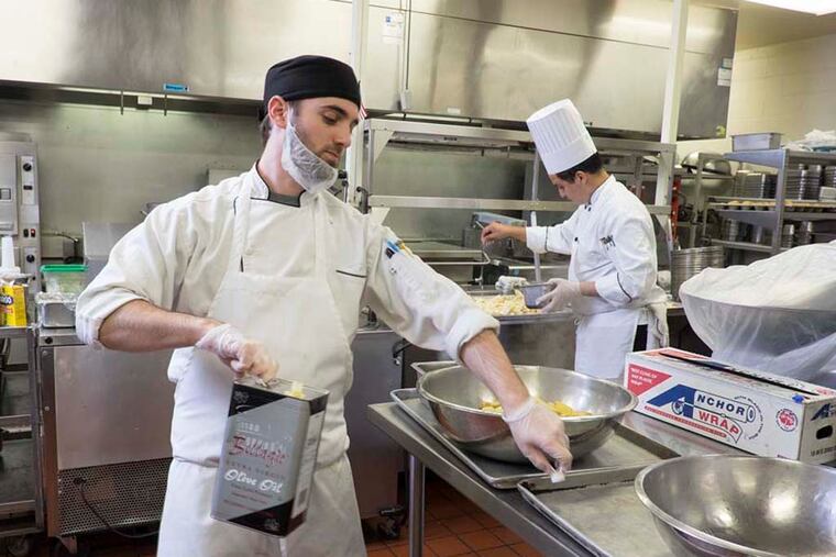 Sous chef Chad Weintraub, front, prepares herb roasted fingerling potatoes as executive chef Youness Jaafar works on a batch of apples and parsnips. ( ED HILLE / Staff Photographer )