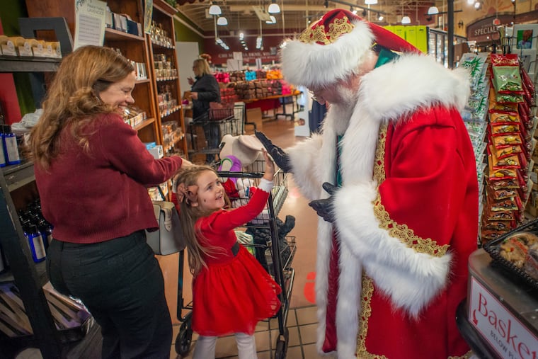 A young girl gives Frank Naimoli, aka "Santa Kringle," a high five during his visit Saturday, Dec. 13, 2025, at Altomonte's Market in Doylestown.