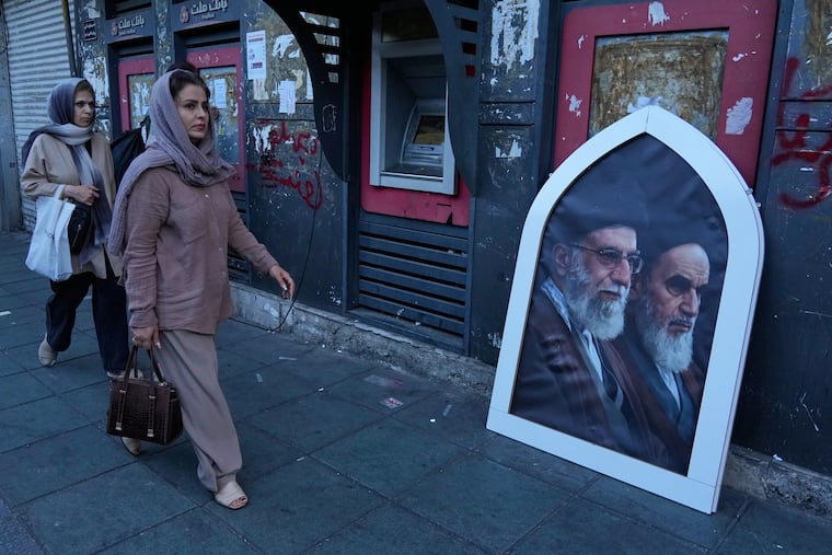 Pedestrians walk past a portrait depicting the slain Iranian Supreme Leader Ayatollah Ali Khamenei, left, and the late revolutionary founder Ayatollah Khomeini on a sidewalk at the Islamic Revolution square in Tehran, Iran, Sunday.
