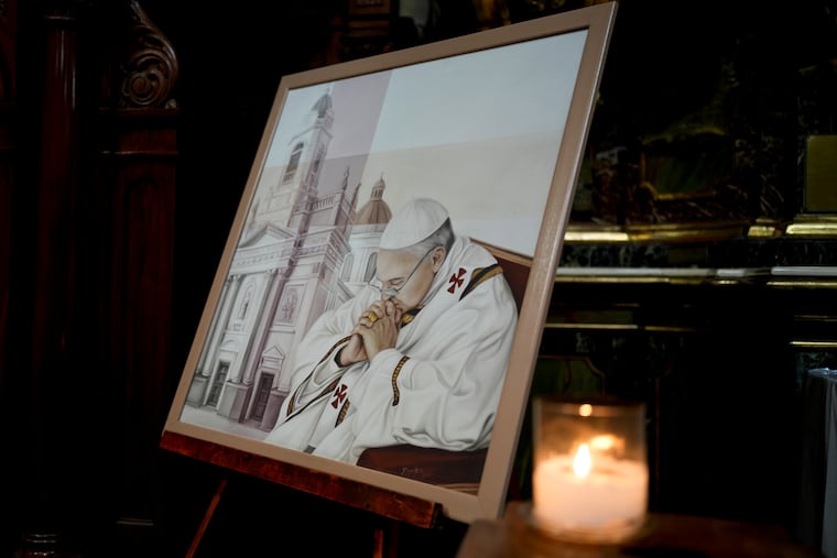 A candle sits alongside a painting of Pope Francis at San José de Flores basilica, Buenos Aires, Argentina, where at 17 years old he first realized his calling to become a priest on Sunday.