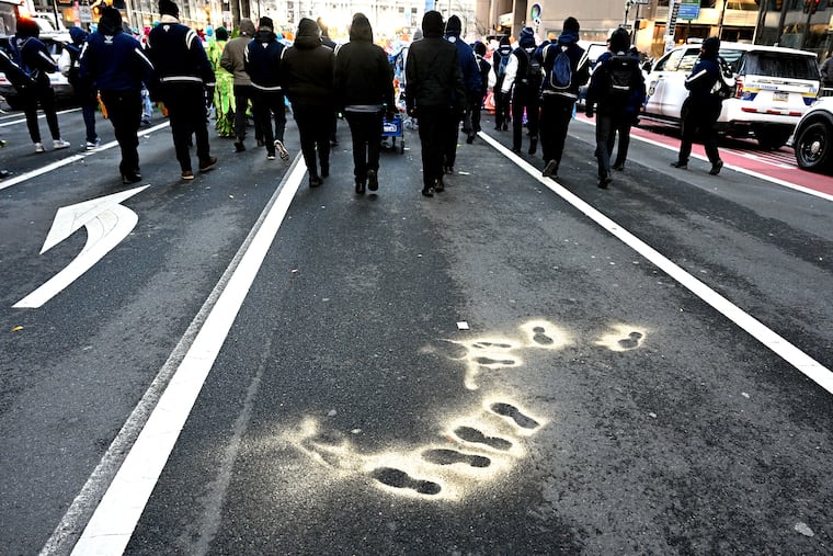 Parade marshals trail behind the musicians of the Greater Kensington String Band heading to their #9 position position start in the Mummers Parade. Spray paint by comic wenches earlier in the day left "Oh, Dem Golden Slippers" shadows on the pavement of Market Street. This year marked the 125th anniversary of Philly’s iconic New Year’s Day celebration.