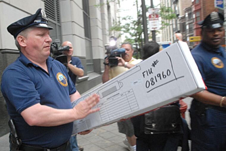 At the Criminal Justice Center, police carry in a box the gun used in the robbery and murder of Liczbinski. (April Saul / Inquirer)