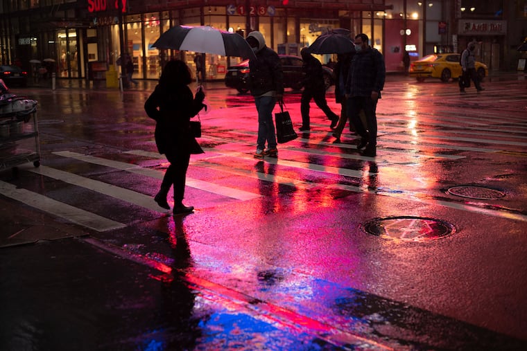 Shoppers walk in a rainstorm Monday in New York. With people staying home as virus cases surge, Cyber Monday was the biggest online shopping day yet, bringing in $10.8 billion in one day. But the entire weekend was disappointing and retailers are bracing for a long winter.