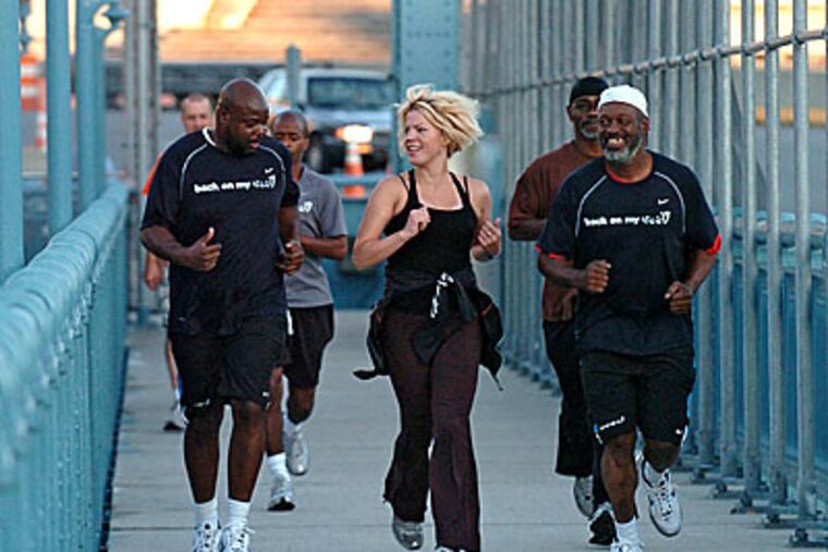 Anne Mahlum, founder of the non-profit Back On My Feet organization, runs up the Ben Franklin Bridge with a group during an early morning jog. ( Clem Murray / Staff Photographer )