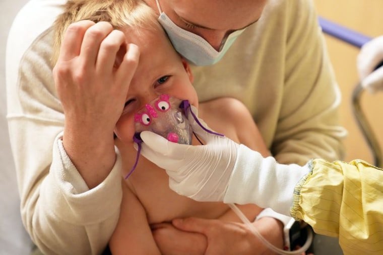 Meredith Legree of Lakeville, Minn., holds her frightened son Andrew, 3, as respiratory therapist Sirena Ortega holds a mask to his face for a nebulizer treatment to help decrease inflammation in his airway and allow him to breathe easier as they waited for the results of his RSV test at Children's Hospital of St. Paul.