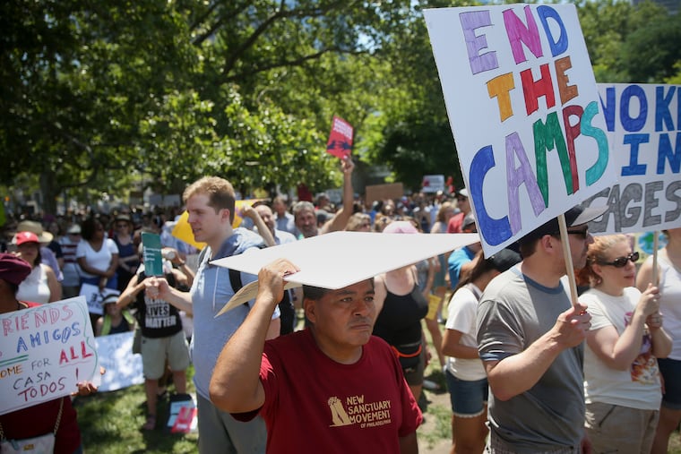 Gerardo Flores, of Philadelphia, a member of the New Sanctuary Movement, shields himself from the sun during a protest against the Trump administration's separation and detention of immigrant families at Logan Square. Similar protests were held elsewhere across the country.