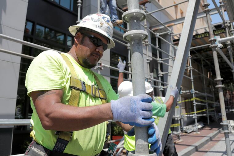 A construction worker helping build a scaffolding on the side of a hotel in the Mount Vernon section of Baltimore.