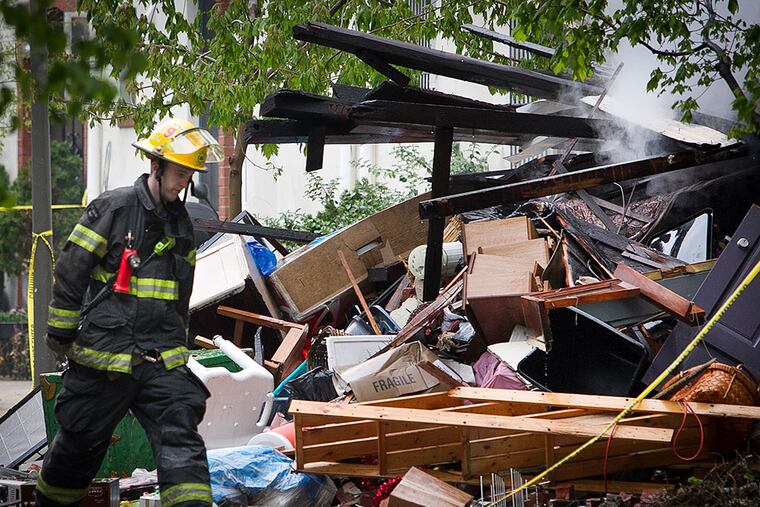 A firefighter walks past the wreckage of a home in the 2300 block of Naudain Street in Center City, destroyed in an explosion early Thursday morning.