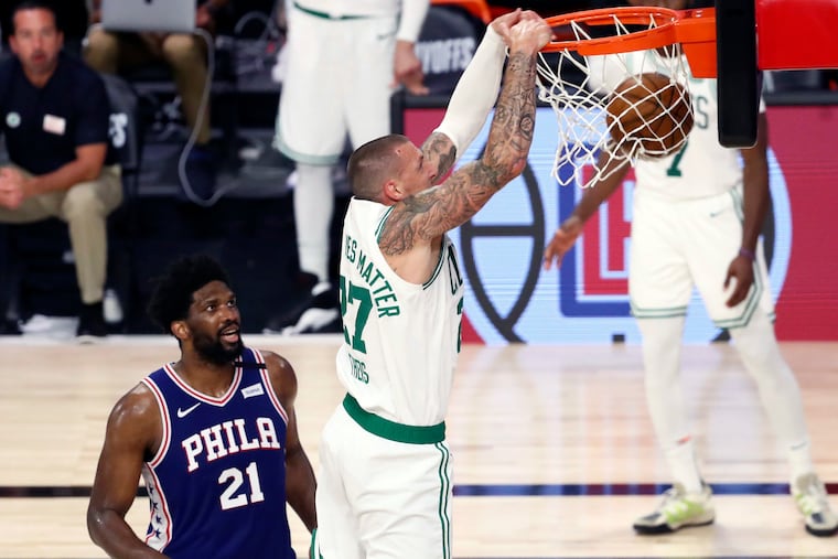 Celtics center Daniel Theis dunks past 76ers center Joel Embiid on Sunday.