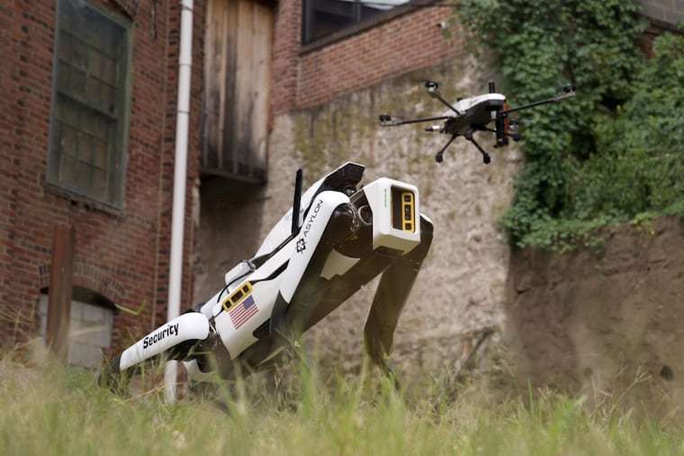 A DroneDog unmanned ground vehicle — a Boston Dynamics Spot-brand robot with a PupPack security package — and an airborne drone at Asylon Robotics headquarters in Norristown.