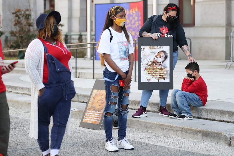 Carmen Pagan, of North Philly, comforts her son, Jace Neal, 6, while holding a photo of her other son, Elijah, who was shot and survived but still has three bullets lodged in his body during a rally to stop gun violence outside of City Hall in Philadelphia on Friday, March 26, 2021.
