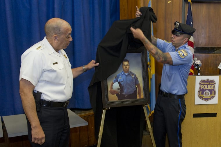 Philadelphia Police Officer Jonathan Castro (right), with some help from First Deputy Police Commissioner Myron Patterson, unveils a portrait of Highway Patrol Officer Brian Lorenzo.
