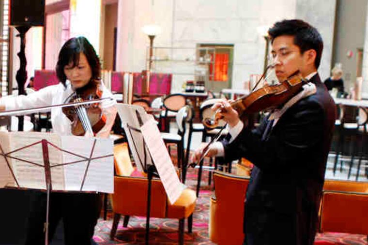 At a media gathering, above, orchestra members (from left) David Kim, Anna Marie Petersen, and Daniel Han play. At left, orchestra president Allison B. Vulgamore stands next to Mayor Nutter.