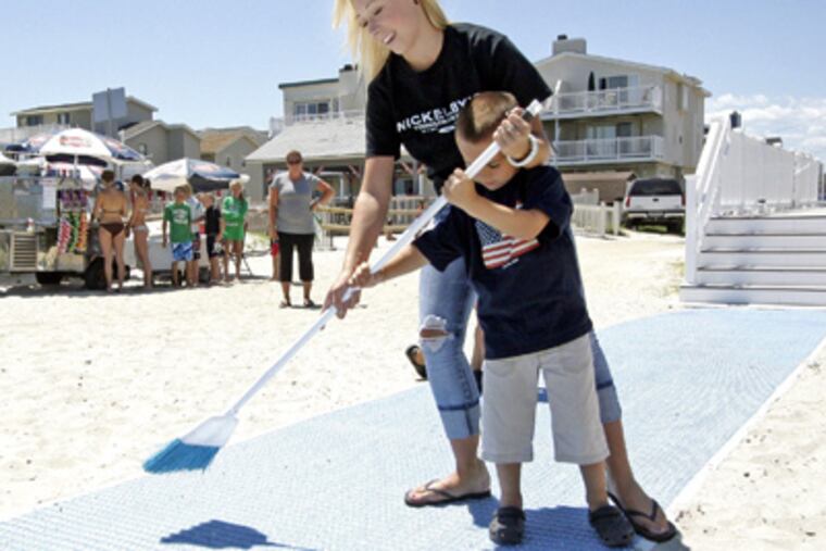 Tori Cookson and brother Noah Grdinich clean a Mobi-Mat in Sea Isle City, N.J. (Elizabeth Robertson / Staff Photographer)