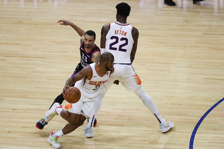 Sixers guard George Hill (left) attemptinng to follow Suns guard Chris Paul around a screen set by center Deandre Ayton in April.