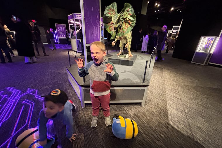 Lachlan McMahon, center, and his cousin.Ashton Campisi, left, pose for a photo at the new exhibit at The Franklin Institute that pays homage to Universal's theme parks, in Philadelphia.