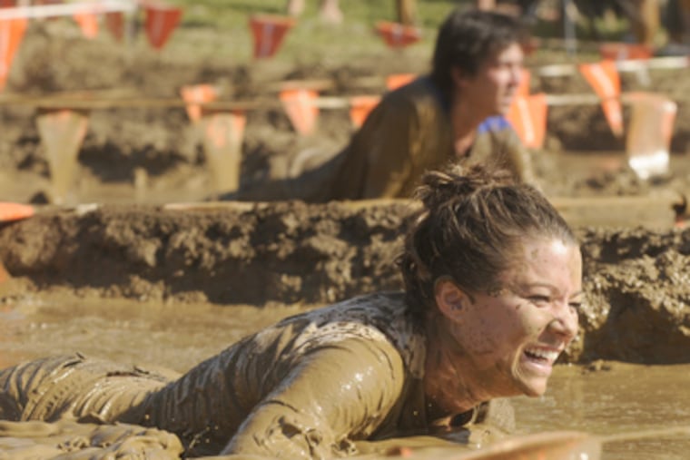 A competitor makes her way through the final mud pit as she finishes the "Down and Dirty Mud Run" on Sunday. (Tom Gralish / Staff Photographer)
