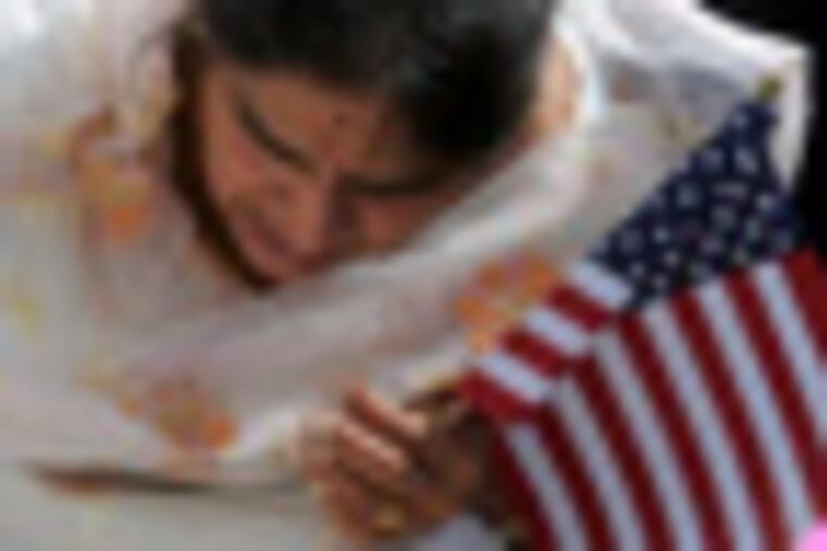Rupinder Kaur Rehal, member of the Blue Mountain Gurdwara, a Sikh temple in Bethel, holds an American flag as she lights candles during a memorial service for the victims of the August 5th shooting at the Sikh temple in Wisconsin, in Bethel, Pa., Sunday, Aug. 12, 2012. (AP Photo/The Republican-Herald, David McKeown)