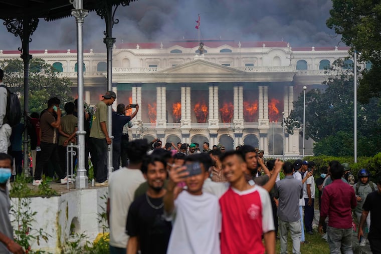 Protesters take selfies and celebrate at the Singha Durbar, the seat of Nepal's government's various ministries and offices, after it was set on fire during a protest against social media ban and corruption, in Kathmandu, Nepal, Tuesday, Sept. 9, 2025.