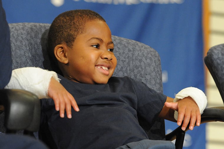 Little Zion Harvey, 8, Baltimore, showing his new hands, smiles at the audience at a press conference at Children's Hospital of Philadelphia July 28, 2015. Zion, who lost his hands and feet to a bacterial disease when he was two-years-old, had a double hand transplant at CHOP in early July 2015, the first pediatric double hand transplant. ( CLEM MURRAY / Staff Photographer )