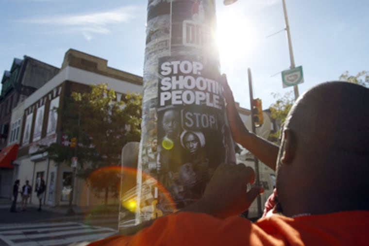 Terry Starks, of Philadelphia Ceasefire, tapes a poster to a light pole near the scene of a shooting on the SEPTA subway at the Susquehanna-Dauphin stop in Philadelphia on September 19, 2012. (David Maialetti / Staff Photographer )
