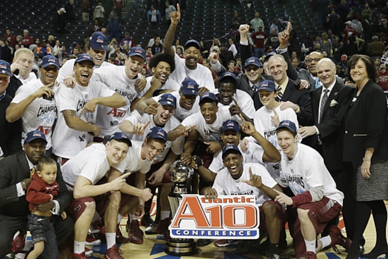 Saint Joseph's players, along with supporters and officials, pose with the championship trophy after beating VCU in the title game of the Atlantic 10 Conference tournament. (Seth Wenig/AP)