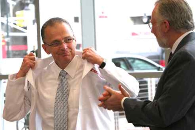 Paul Katz accepts a lab coat from Rowan University president Donald Farish. Katz, who was introduced at a news conference Wednesday, will serve as dean of Rowan's new medical school.