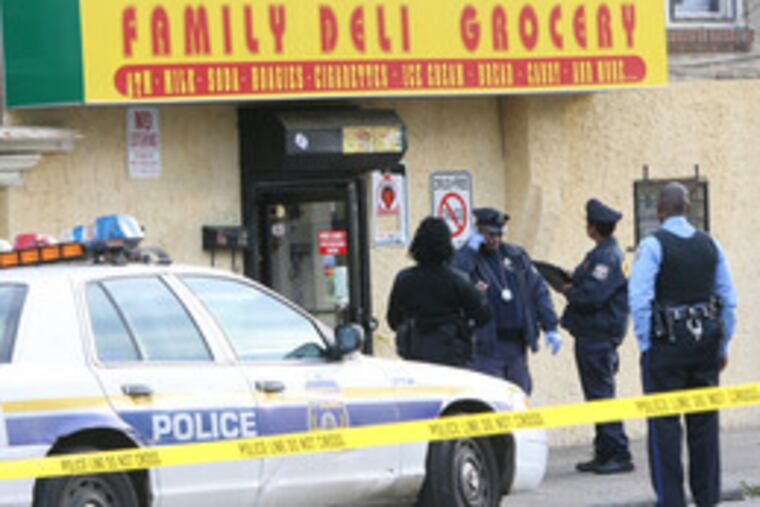 Cops investigate a crime scene on Cornelius Street in Germantown yesterday. A grocery-store clerk, identified as a 20-year-old woman, was shot dead.