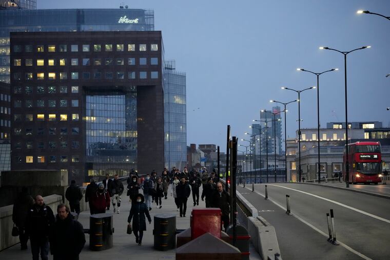 Workers walk over London Bridge towards the City of London financial district during the morning commute, in London, on Monday.