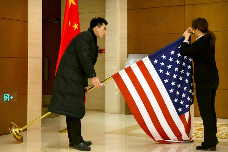 In this Feb. 14, 2019, file photo, Chinese staffers adjust a U.S. flag before the opening session of trade negotiations between U.S. and Chinese trade representatives at the Diaoyutai State Guesthouse in Beijing. Economist Mark Zandi looks at Trump's trade war with China and where the presidential candidates stand on trade, tariffs, and tax cuts, along with managing COVID-19. (AP Photo/Mark Schiefelbein, Pool, File)