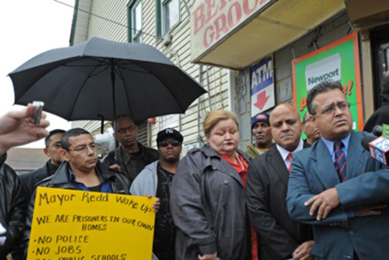 Outside the Bernard Grocery at 27th and Pierce in Camden, mourners and politicians try to make sense of the shooting that took the life of owner Miguel Almonte. Here, politicians, including Assemblyman Angel Ortiz, right; and Camden City Council president Frank Moran, next to him, call for a state of emergency in Camden. 12/06/11 ( APRIL SAUL / Staff Photographer )