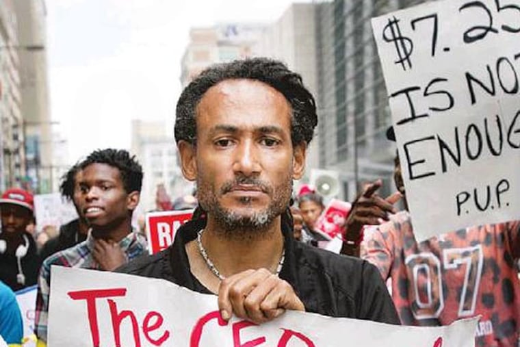 Glenn Davis of Philadelphia marches with other protesters and fast food workers down N. Broad St. towards Arch on Thursday morning. A large group of anti low wage fast food workers and supporters gathered to protest in front of the McDonalds and N. Broad and Girard Ave on Thursday morning May 15, 2014. This group is demanding a wage increase for fast food workers. (Alejandro A. Alvarez / Staff Photographer)