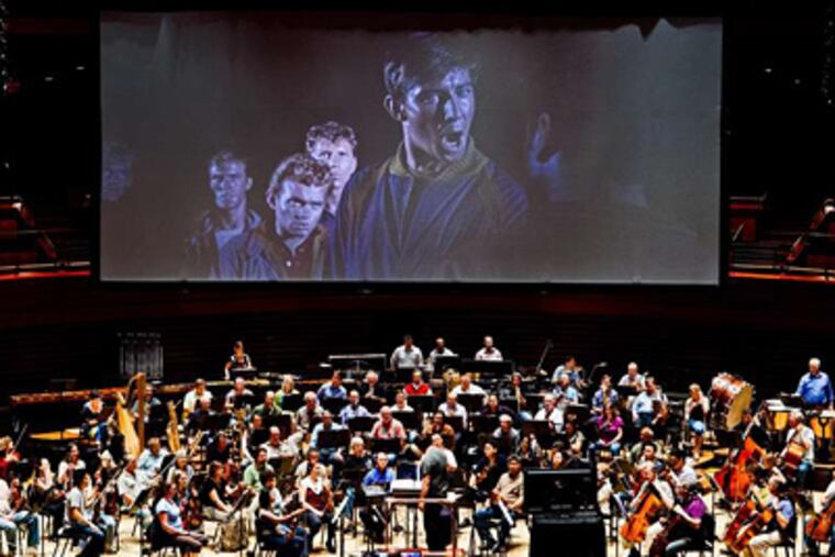 With "West Side Story" playing on the screen behind, the Philadelphia Orchestra rehearses. DAVID M WARREN / Staff