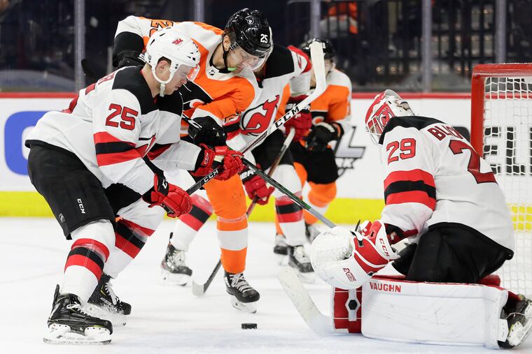 Flyers left winger James van Riemsdyk battles for a loose puck against New Jersey goaltender Mackenzie Blackwood (left) and the Devils' Mirco Mueller (right) during a Feb. 6 game.